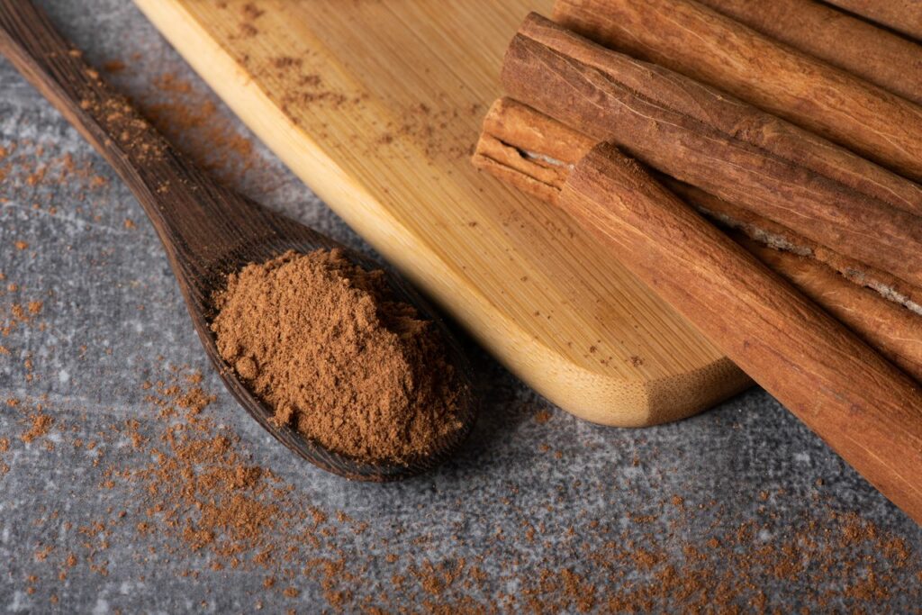 Canela en rama y molida en una cuchara sobre fondo de madera